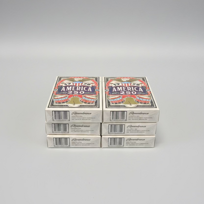 Six decks of the Remembrance America 250 playing cards stacked in two columns on a gray surface