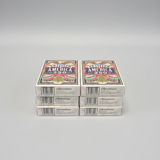 Six decks of the Remembrance America 250 playing cards stacked in two columns on a gray surface